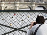 „Reuters“/„Scanpix“ nuotr./Turistas fotografuoja spynas ant Pont des Arts tilto turėklų.