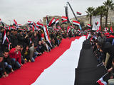 „Reuters“/„Scanpix“ nuotr./Žmonės tiesia Sirijos vėliavą, rodydami pagarbą prezidentui